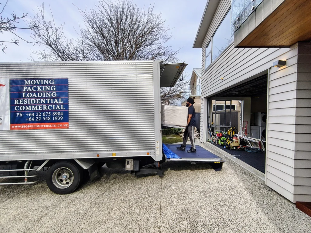 Mover loading household furniture into a truck in Auckland